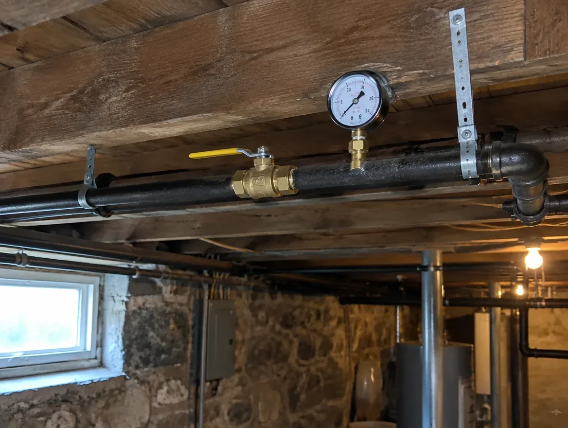 Black iron gas piping and a gas meter connection in a Greater Boston basement, sized and installed by Prime Plumbing