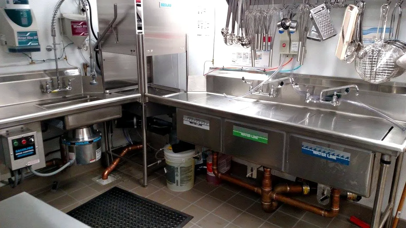 Commercial kitchen dish station with a three-compartment sink, disposal, and copper drains plumbed by Prime Plumbing in Greater Boston