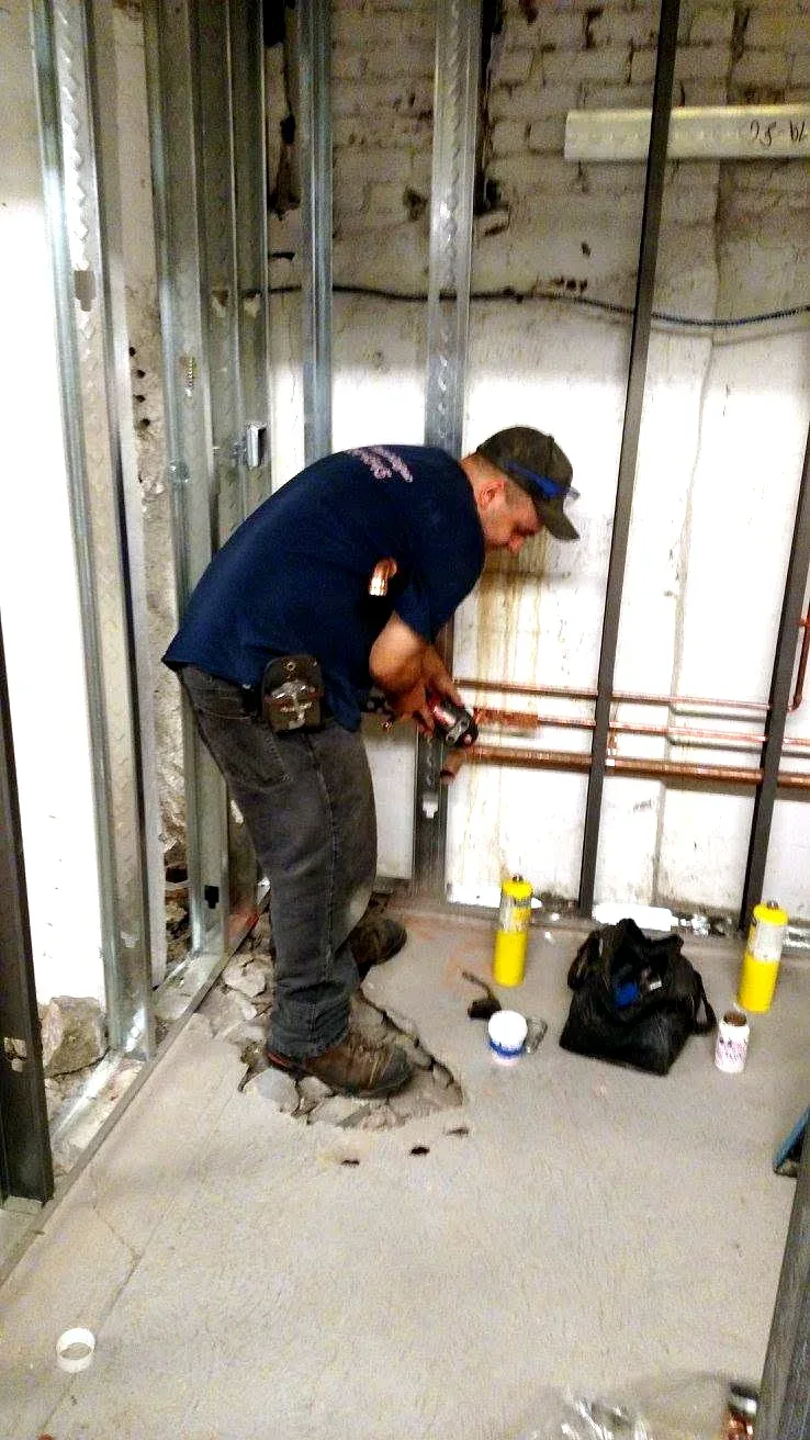 Prime Plumbing technician soldering copper supply lines in a framed wall during a Greater Boston renovation