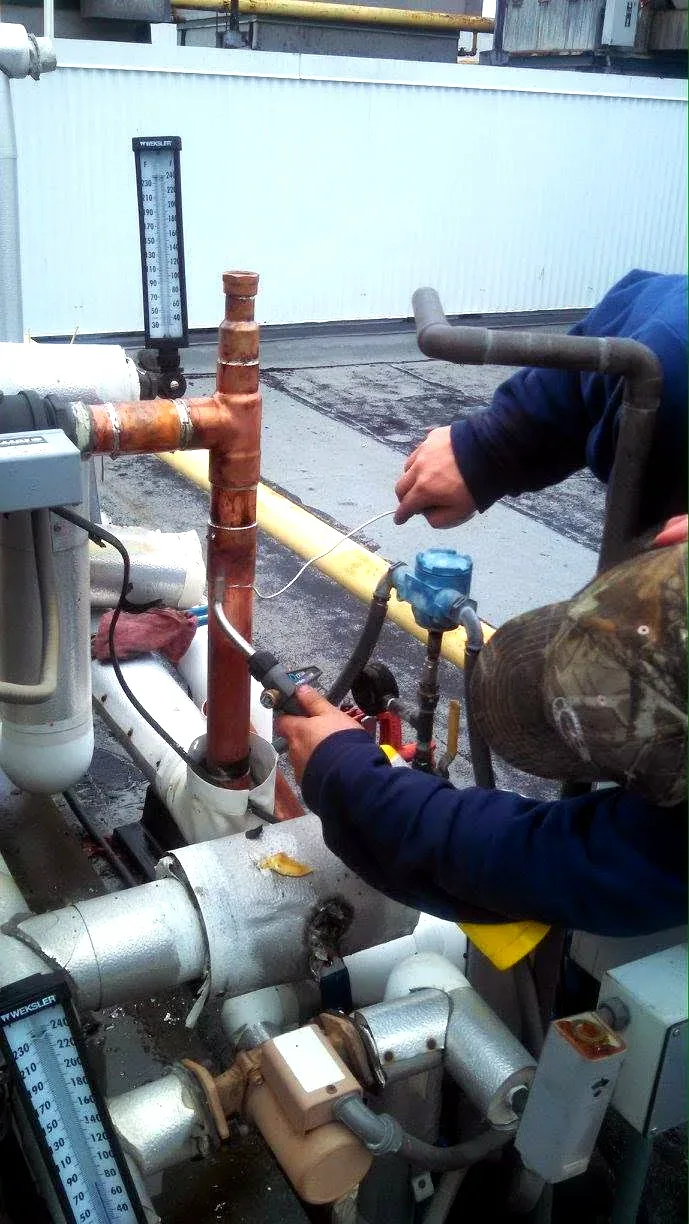 Prime Plumbing technician servicing rooftop commercial mechanical piping and gauges in Greater Boston