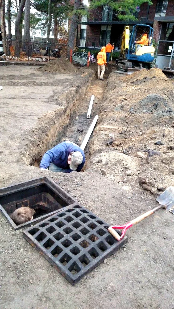 Prime Plumbing crew installing a sewer line in an excavated trench at a Greater Boston property